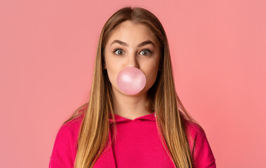 Bubble from chewing gum. Teenage girl on pink background