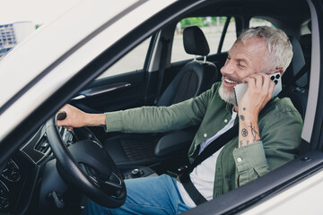 Photo of funky cool mature guy dressed casual shirt driving auto talking modern device outdoors...