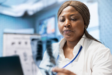 Woman medic examining radiography test results in medical cabinet, ensuring the perfect treatment...