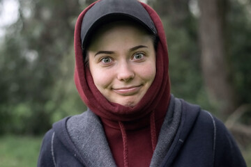 A funny girl in a cap and hood with a strange smile and a look in nature_2