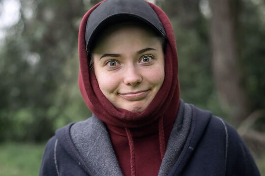 A funny girl in a cap and hood with a strange smile and a look in nature_2