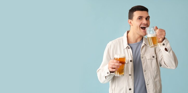 Handsome young man drinking beer on light blue background with space for text - Powered by Adobe
