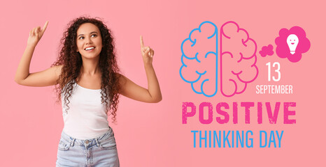 Happy young African-American woman pointing at something on pink background