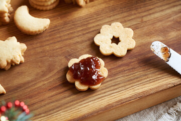 Filling a flower shaped Linzer Christmas cookiew with strawberry marmalade,