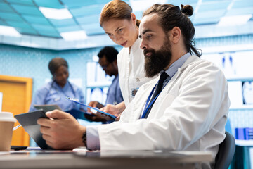 Fototapeta premium Doctors team working in a medical treatment center to find diagnosis. Professional experts engaged in a meeting about checkup test results in a private clinic, healthcare industry teamwork.