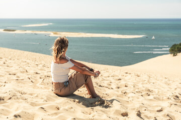 Chica sentada en la dune du pilat, la mayor duna de europa, para disfrutar y relajarse