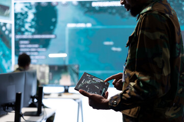High tech military office with soldiers analyzing real time data, processing intelligence information and coordinating strategic operations to support army field missions effectively.