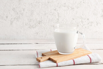 Glass cup with fresh milk on light wooden table