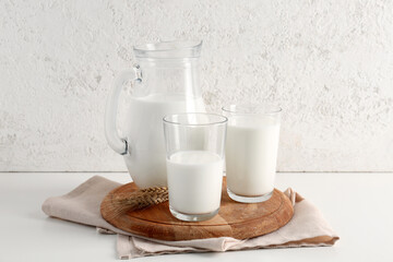 Jug and glasses with fresh milk on white background
