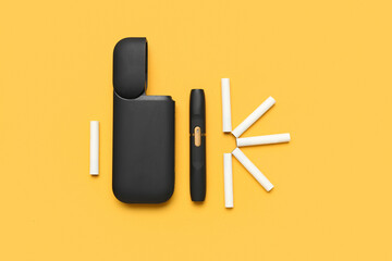 Modern electronic cigar and sticks on orange background