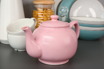 Composition with teapot, cups and different kitchen stuff on black table