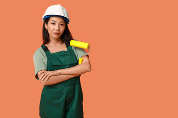 Female Asian painter with roller on orange background