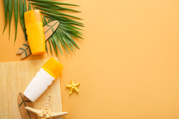 Bottles of sunscreen cream, starfishes, palm leaves and surfboard on orange background
