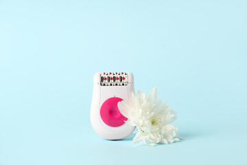 Modern epilator with flower on blue background