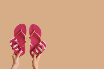 Hands with female and kid flip flops on beige background