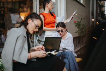 Focused businesswomen having an outdoor meeting, discussing documents and working on laptops, showcasing teamwork and concentration.