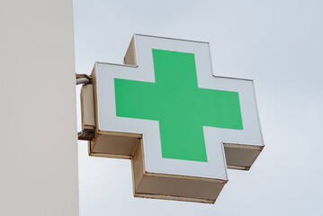 green cross symbol of pharmacy, attached to wall