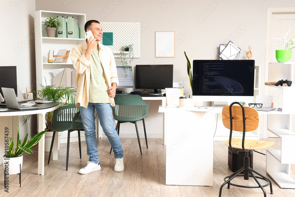 Poster handsome programmer talking by mobile phone in office