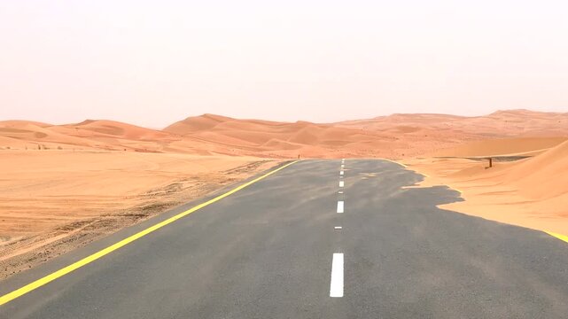 Desert road with sand blown onto asphalt, basking in bright sunlight. Scene captures rugged beauty of desert and relentless encroachment of sand on path Concept Desert Adventure Road Trip