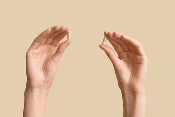 Female hands with pills on beige background