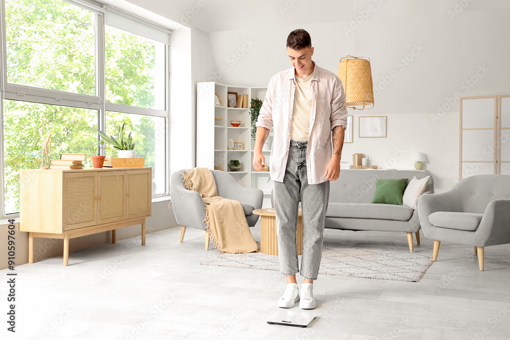 Canvas Prints Young man measuring his weight on scales at home