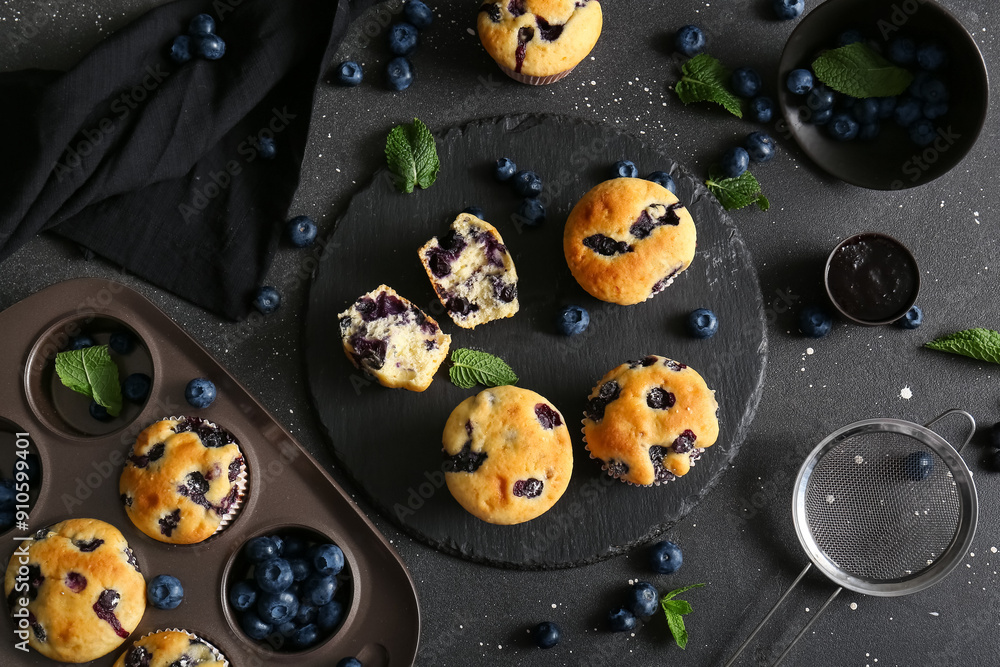 Wall mural baking and stone trays with tasty blueberry muffins on black background