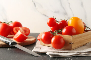 Tomatoes on cutting board with knife on table against white grunge background. Closeup