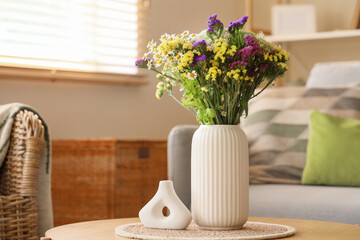 Wild flowers in vase on coffee table in living room. Closeup