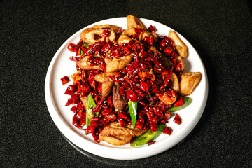 Spicy Dry fried Pigs Intestines with red chilli pepper with chopsticks served in dish on dark background top view of hong kong food