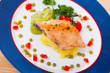 Deliciously fried trout fillet with mashed potatoes, guacamole and greens on white plate
