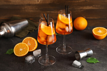 Glasses of Aperol spritz cocktail with fruits and shaker on black table