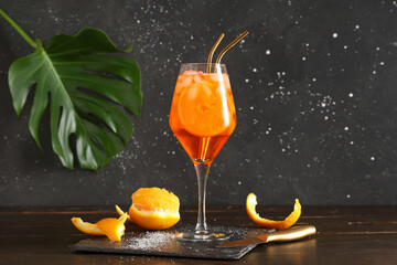 Glass of Aperol spritz cocktail and palm leaf on wooden table