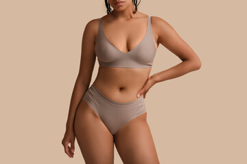 Young woman in underwear on beige background
