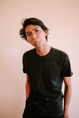 A Southeast Asian man frowns with furrowed brows, dressed casually. His expression conveys...