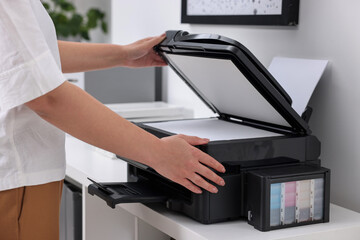 Woman using modern printer at workplace indoors, closeup