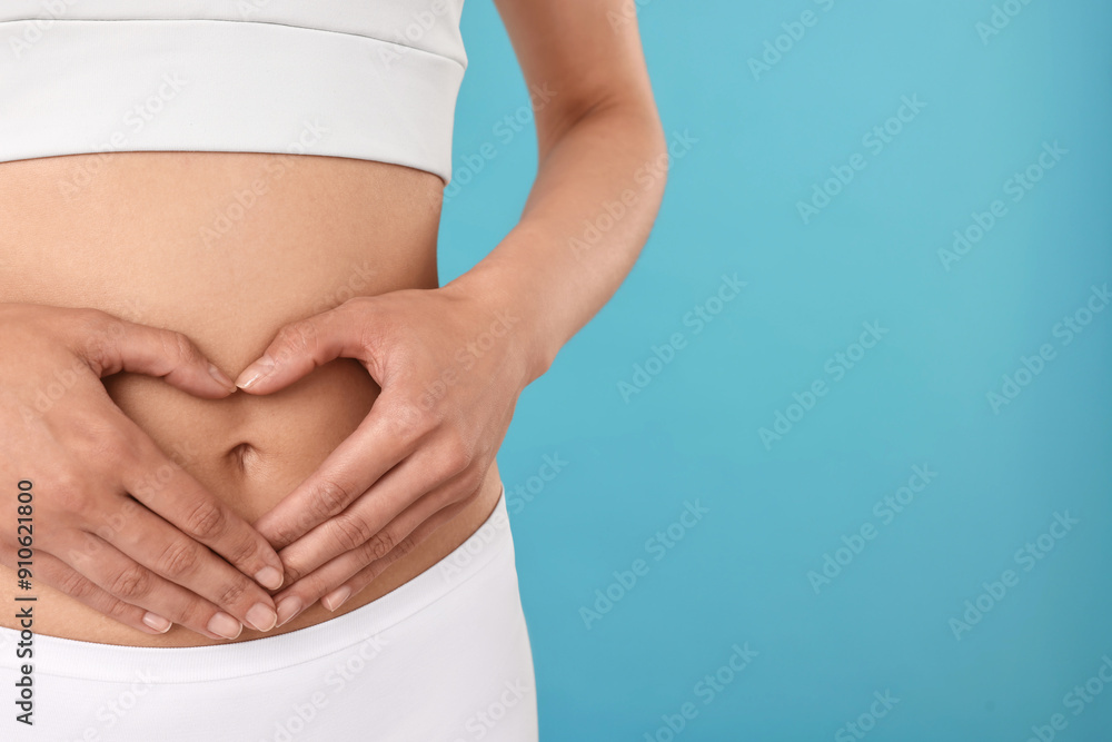 Poster Healthy digestion. Woman making heart shape with hands near her belly on light blue background, closeup. Space for text