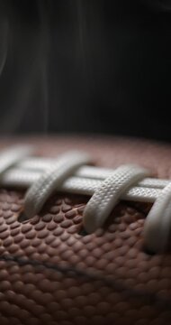 Football ball macro rotating with smoke in studio slow motion, vertical view