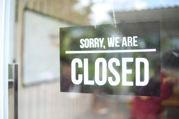 A Black Sign Hanging On Glass Door That Reads Sorry, We Are Closed.
