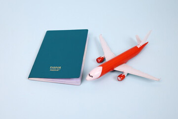 High Angle Of Green Passport And a Red Toy Airplane Isolated On Light Blue Background.
