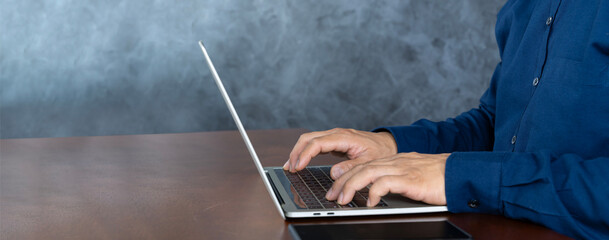 Close up businessman typing on a laptop computer at home. A man browsing the internet at home.