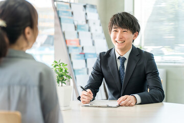 女性客と商談する若いアジア人ビジネスマン（自動車・保険）
