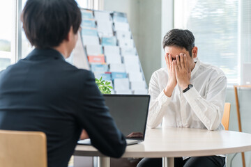 自動車保険の相談に来た中年男性と接客対応する男性ビジネスマン
