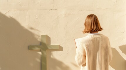 Woman Reflecting on Good Friday Morning With a Book and Cross Against Beige Wall - Mid 20s, Caucasian, Peaceful, Introspective Mood