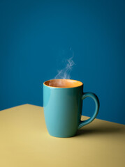 Blue hot cup of coffee with smoke on pastel blue background, copy space