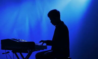 Silhouette of Keyboard Player Absorbed in Music with Blue Background