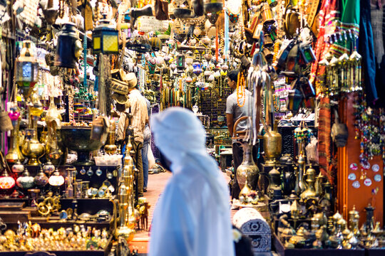 Man with arabic tunic walking past souvenir shop in the bazaar, Muscat, Oman