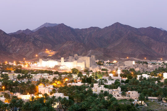 Bahla fort and city at dusk with mountains in the background, Oman