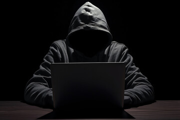 Anonymous hacker with black hoodie working on computer laptop