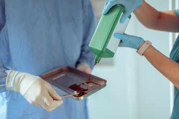 Doctor and Nurse Disinfecting Instruments Tray in the Emergency Room. Health care workers using povidone-iodine medication for sterilizing instruments 

