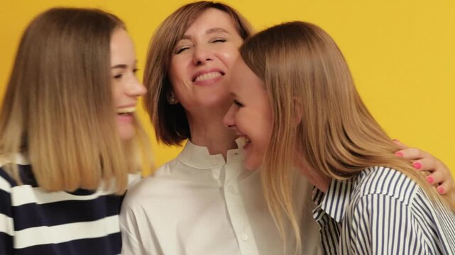 Happy women fun conversation. Three amused cheerful female friends enjoying speaking laughing together isolated on yellow background.